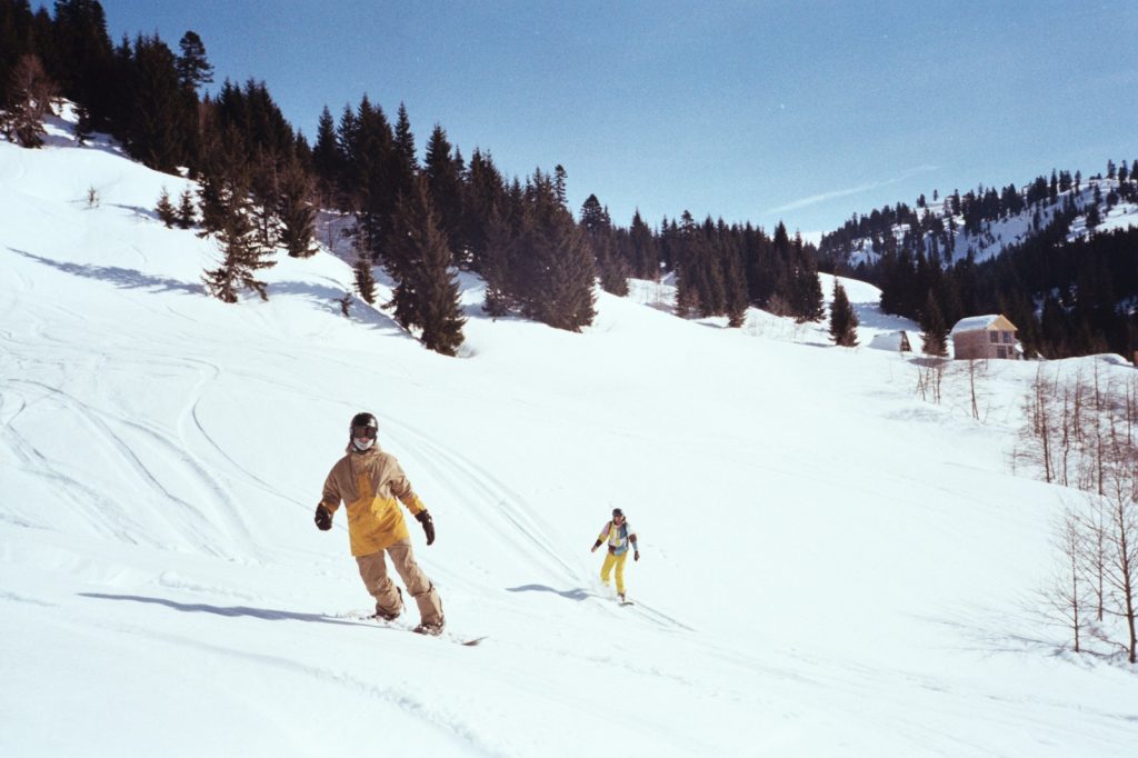 A couple of people riding skis down a snow covered slope